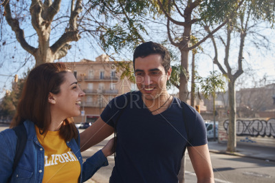 Young couple walk arm in arm along a city street