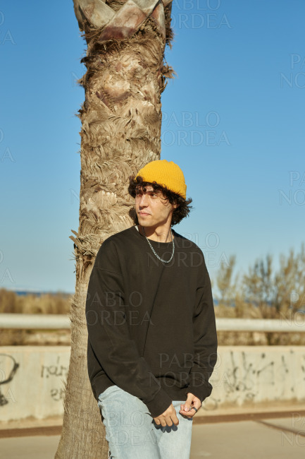 A distant young man relaxing against a tree
