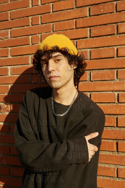 Attractive guy looking at you against brick wall stock photo