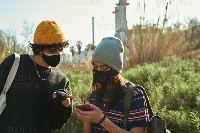 Cute couple discussing something on phone outdoors