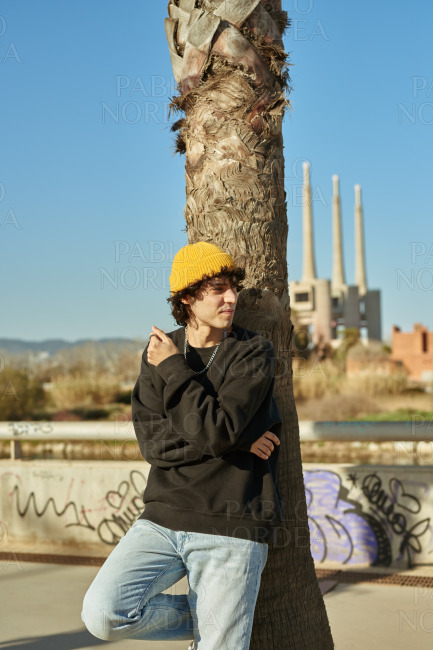 Handsome young man leaning on tree