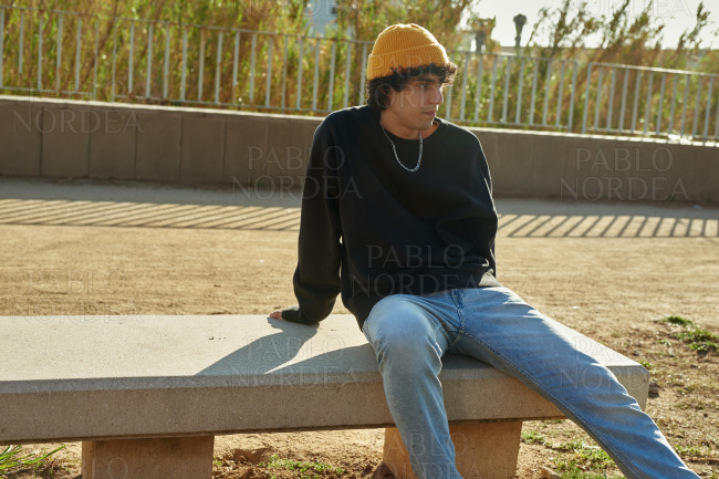 Handsome young man sitting on bench outdoors