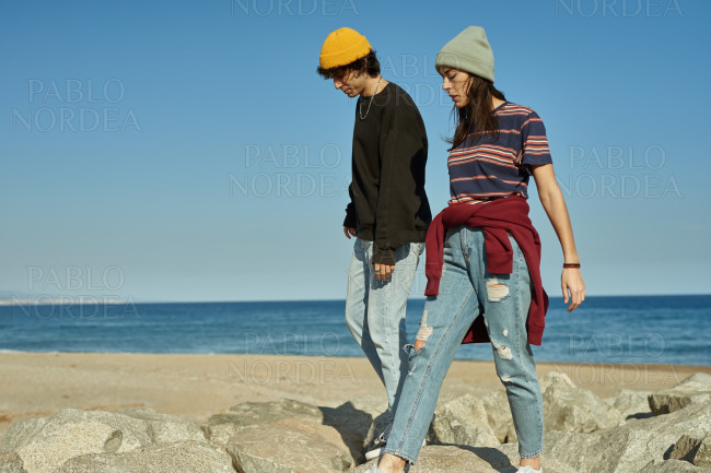 Two blissful young people walking along the beach