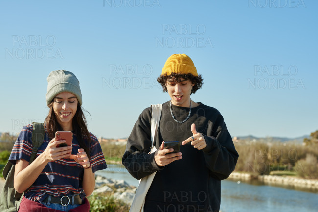 Two busy young people texting and walking