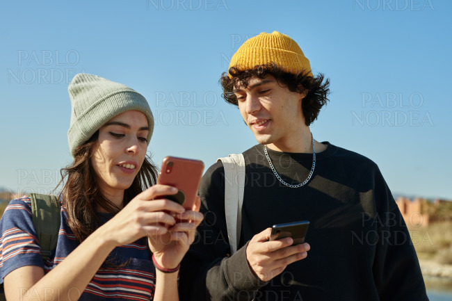 Two serene young people talking and texting