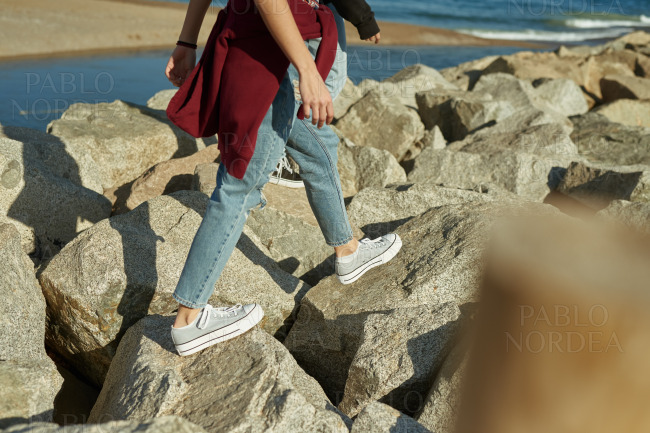 Two young people walking on rocks along the beach