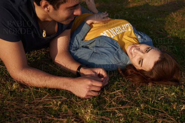 Woman smiles at the man as they lay on the grass