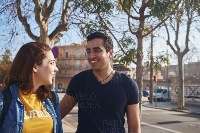 Young couple smile at each other as they walk stock photo