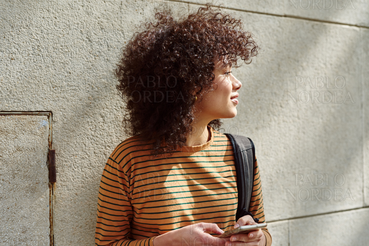Cute girl looking away while holding cellphone stock photo