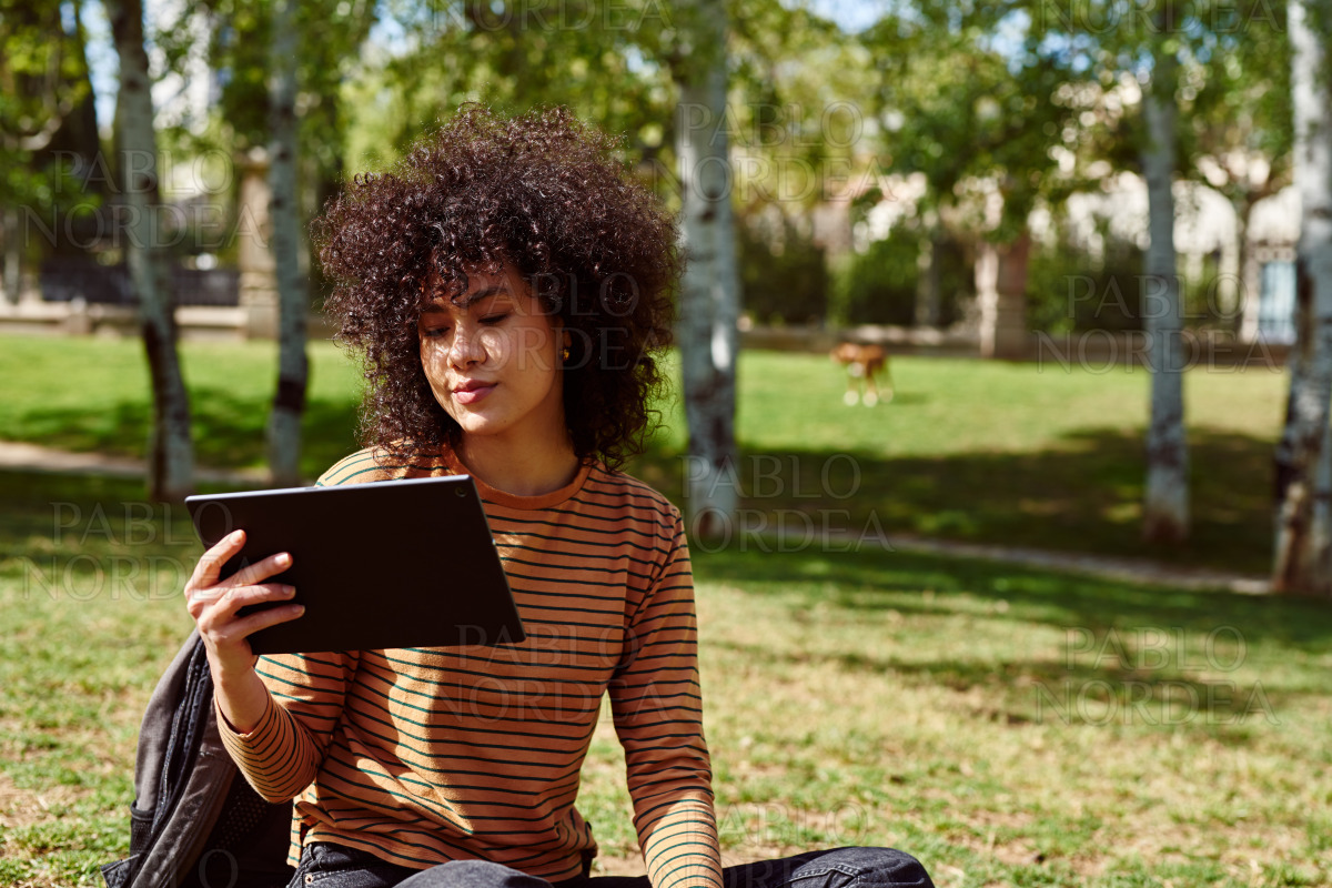 Cute young woman using a digital tablet in a park stock photo