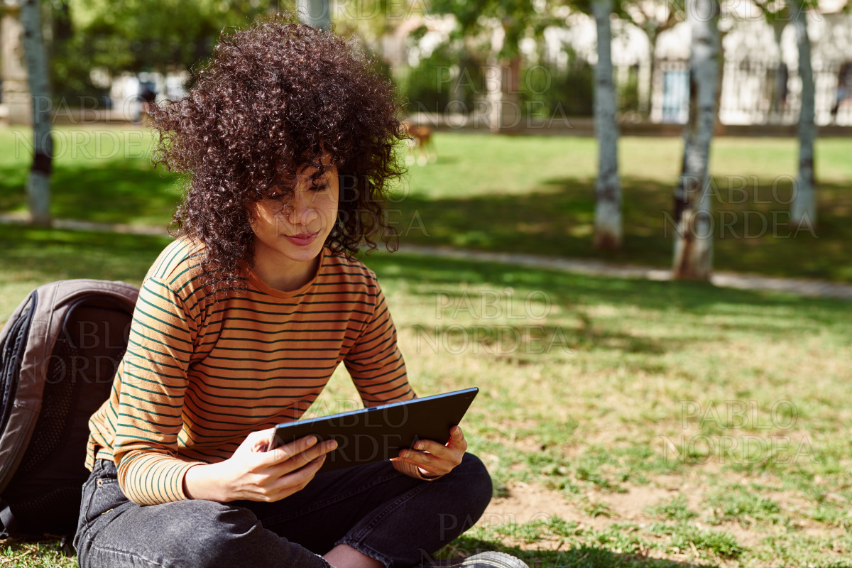 Cute young woman using a tablet pc in a park stock photo