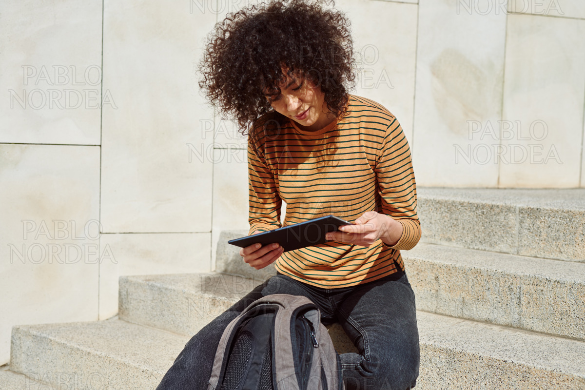 Girl reading from her tablet pc outdoors stock photo