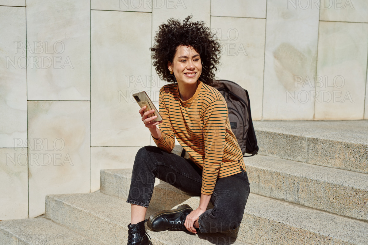 Smiling black girl using cellphone outdoors stock photo