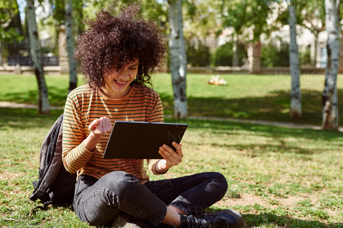 Young woman celebrating while holding a tablet pc stock photo