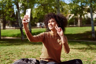 Attractive young woman taking a selfie in a park