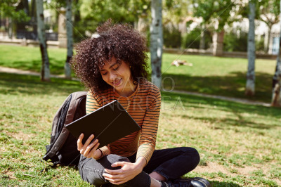 Attractive young woman using a tablet pc in a park
