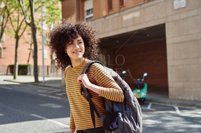 Smiling black girl crossing a street outdoors
