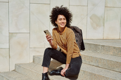 Smiling black girl using cellphone outdoors