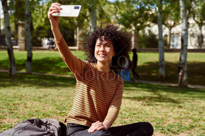Smiling girl taking a selfie in a park