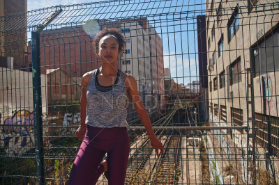 Sporty young black woman standing next to a fence