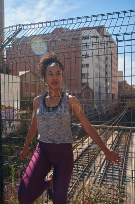Sporty young woman standing next to a fence