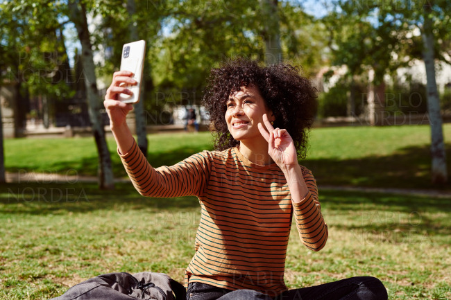 Attractive young woman taking a selfie in a park