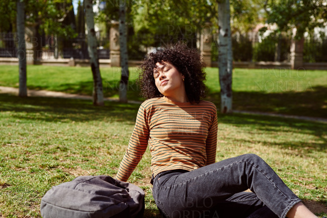 Cute young woman enjoying the sun in a park stock photo