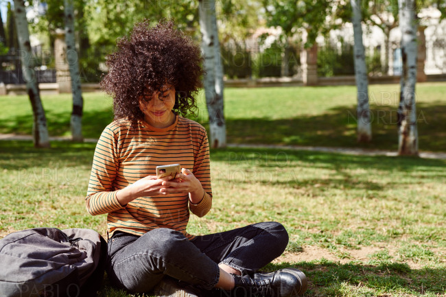 Cute young woman sending a message in a park