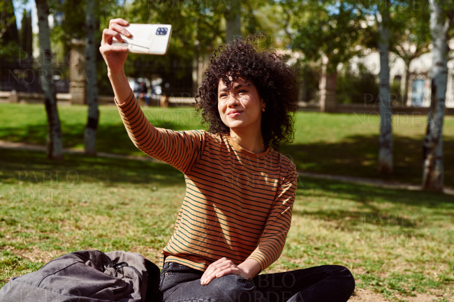Cute young woman taking a selfie in a park