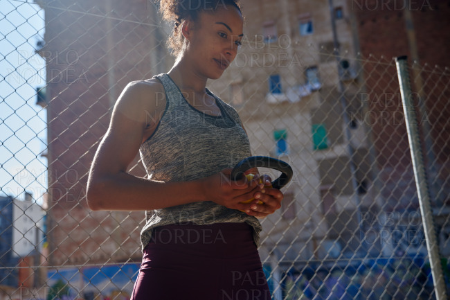 Dedicated young woman holding a dumbbell outdoors