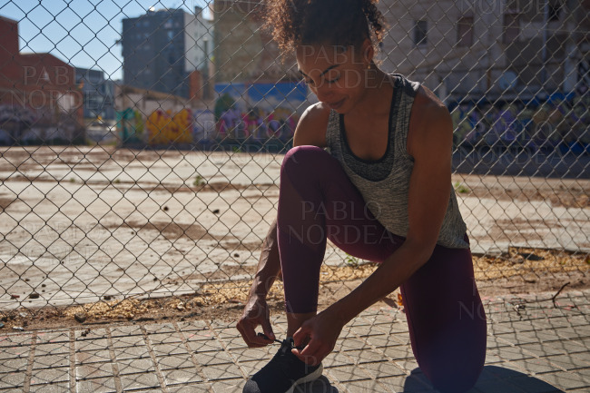 Fit young black woman tying her shoelaces