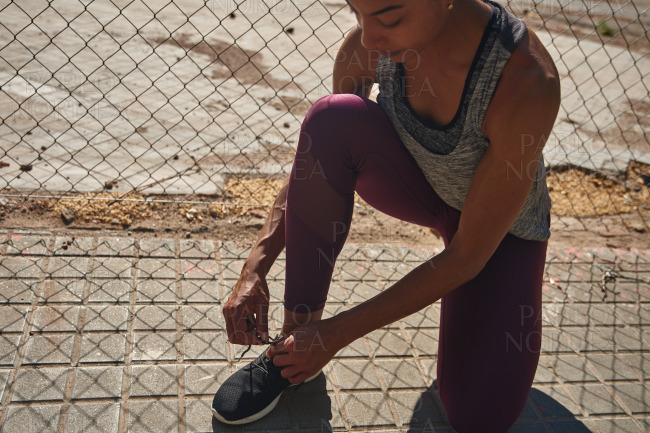 Fit young black woman tying her shoelaces outdoors