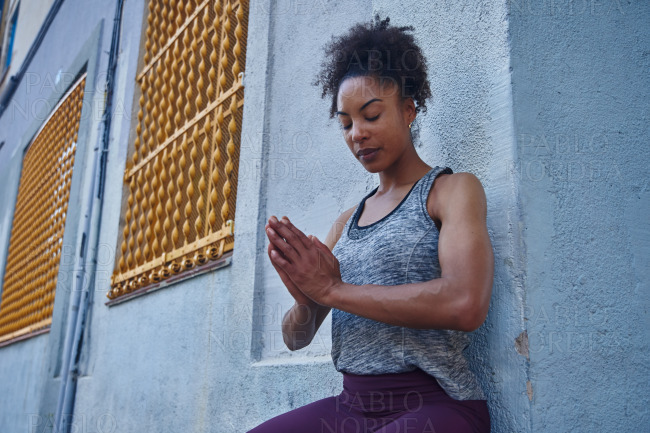 Fit young woman meditating in gym clothes