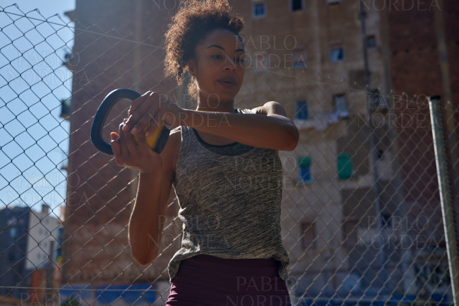 Focused black woman working out with a dumbbell