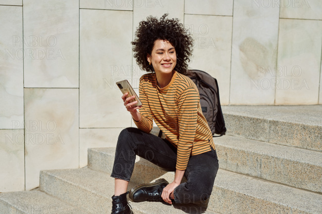Smiling black girl using cellphone outdoors