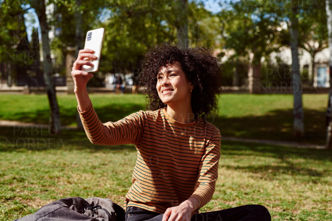 Smiling young woman taking a selfie in a park