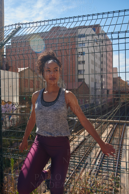 Sporty young woman standing next to a fence