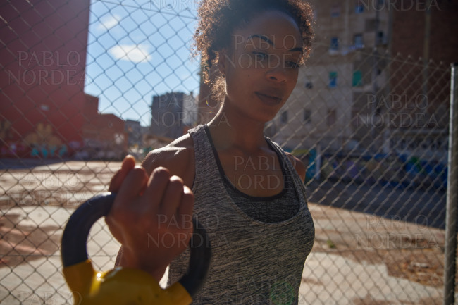 Young black woman holding a dumbbell outdoors
