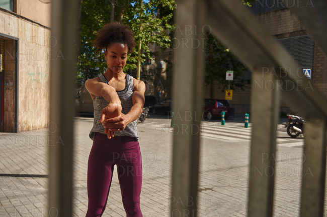 Young black woman stretching her hands outdoors