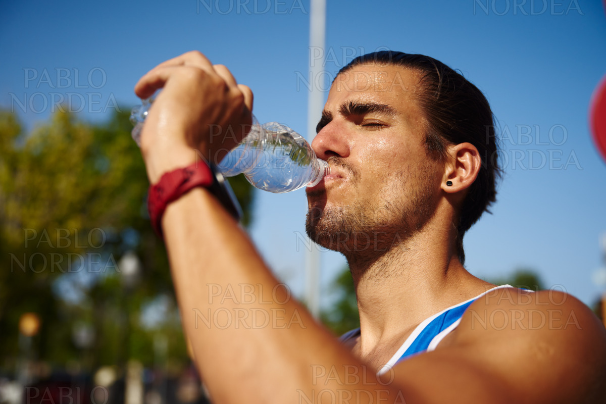 Athletic young man drinking water outdoors stock photo