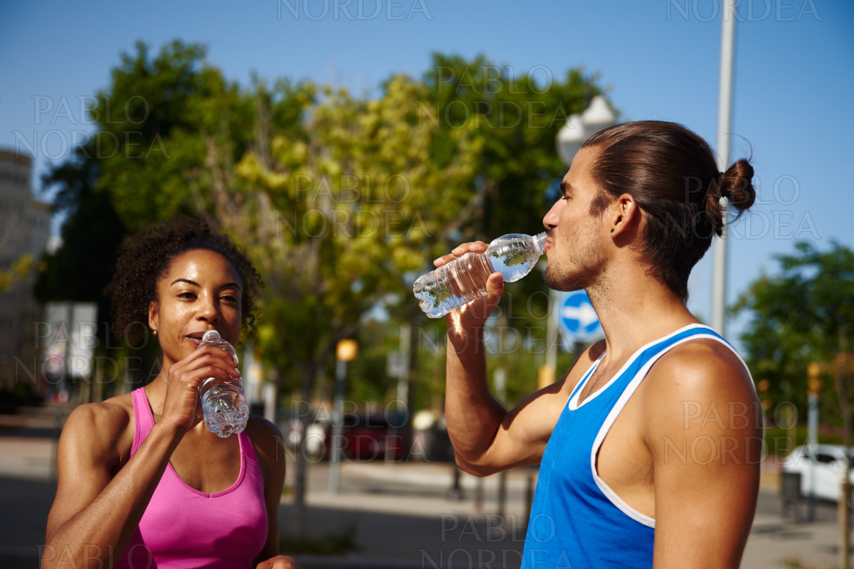 Fit young couple drinking water outdoors stock photo
