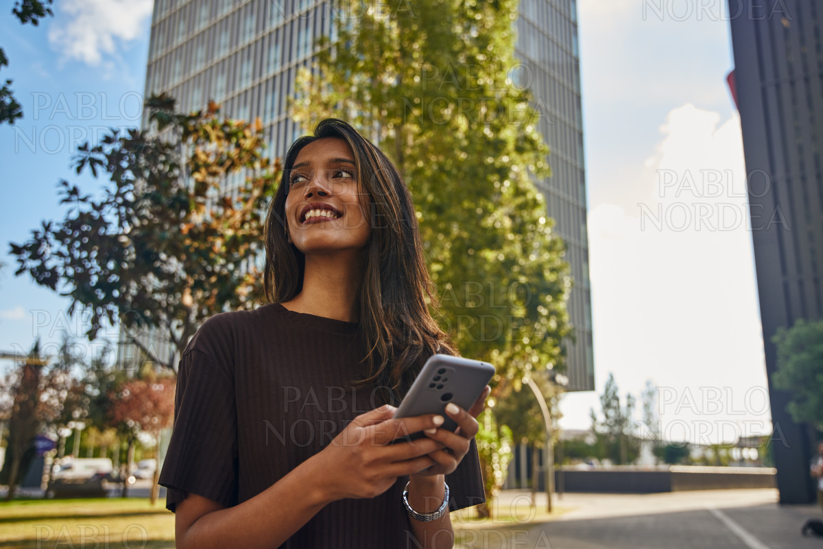 Happy businesswoman with mobile phone on street stock photo