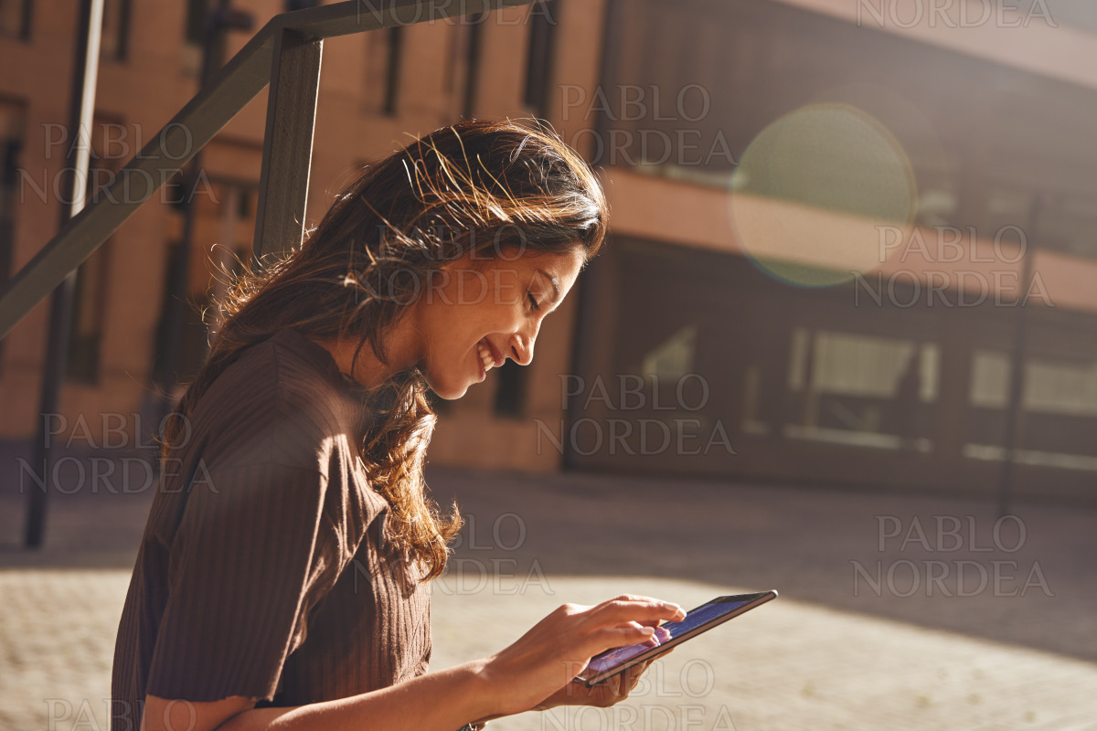 Young confident woman using tablet on street stock photo