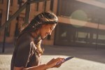 Young confident woman using tablet on street