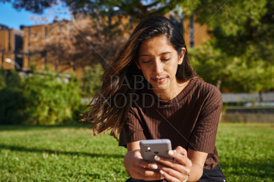 Businesswoman sitting and text messaging in park