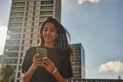 Laughing businesswoman standing and text messaging