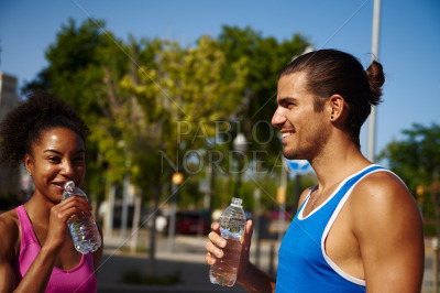 Smiling young couple drinking water outdoors