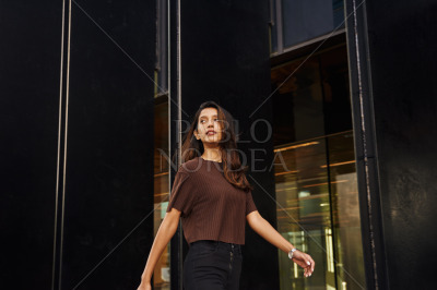 Stylish businesswoman walking on street with phone