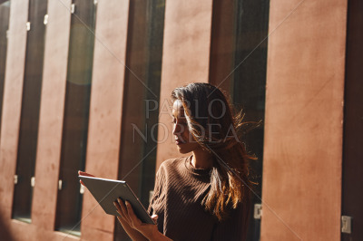Young attractive businesswoman using tablet in sun