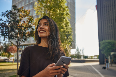 Young businesswoman with mobile phone in sun